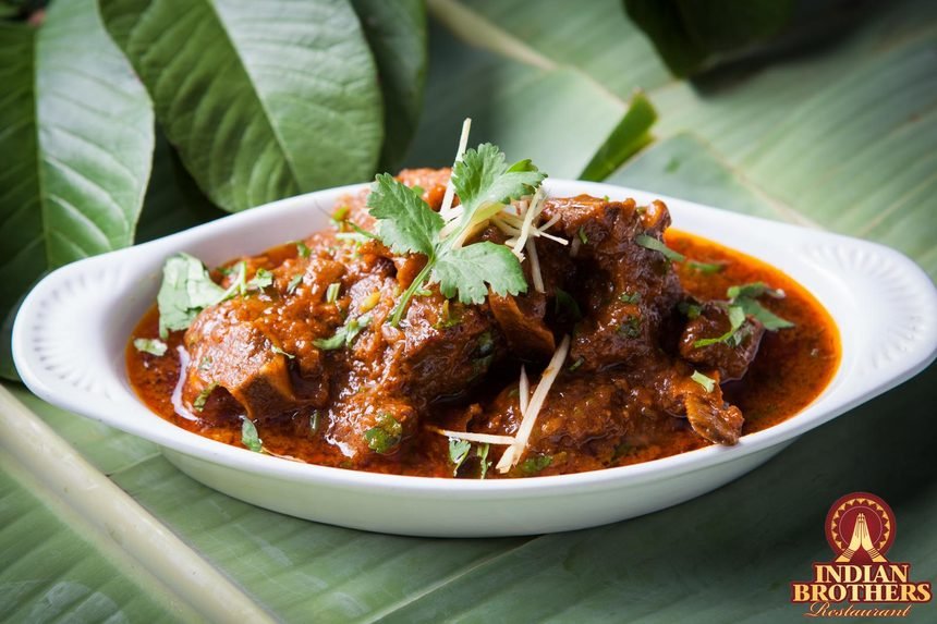 Slow-cooked bone-in goat curry in a dark, robust masala